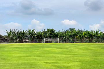 View of a huge football field with a green fresh lawn surrounded by palm trees and trees in Indonesia on the island of Bali