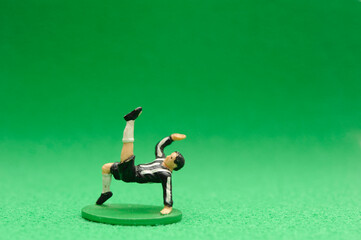 miniature toy figurine soccer player on green background with copy space