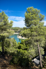 Fototapeta premium Spectacular panoramic views of the Guadalhorce reservoir, next to the Caminito del Rey in Malaga, Spain. Turquoise blue water and forest with blue sky on a sunny day.