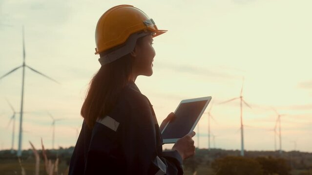 a woman engineer is wearing a protective helmet on her head, using tablet Analytics engineering data..