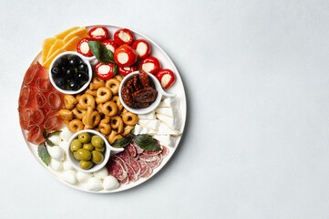 Classic italian antipasti or tapas wine snacks set. Cheese variety, black and green olives, pickles, prosciutto di Parma, tomatoes, salami, tarallini. Flat lay, top view, copy space for text
