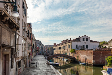 Fototapeta na wymiar Scenic view of canal and old stone bridge in Venice, Italy, at sunset