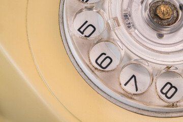 Dialing disc of an old yellow telephone with round holes and numbers. Macro shot of retro rotary...