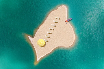 A lot of deck chair with umbrella and sup board on a small uninhabited, desert sand island  in the...