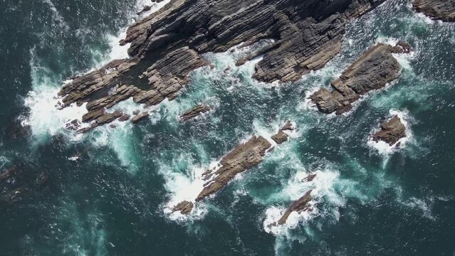 Aerial view of waves breaking on the cliffs at Cabo de Farol Sardao facing the Atlantic Ocean in Vila Nova de Milfontes, Alentejo region, Portugal.