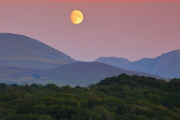 The Moon rising over the Mountains of Snowdonia from Anglesey, North Wales, UK.