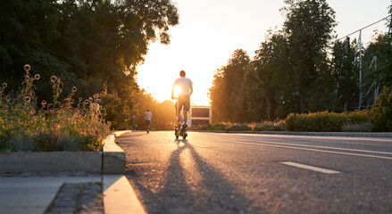 Man is riding on electric scooter or e-scooter on the street on the sunset. © nuclear_lily