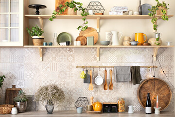 Stylish scandi cuisine interior decor. Ceramic plates, dishes, utensils and cozy decor on wooden shelfs. Kitchen wooden shelves with various ceramic jars and cookware. Open shelves in the kitchen. 