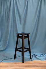 black minimalist wooden chair against blue background. Concept modern interior and design furniture in room. High stool in loft style. Retro Bar chair. Vintage wooden chair. Tall standing table.