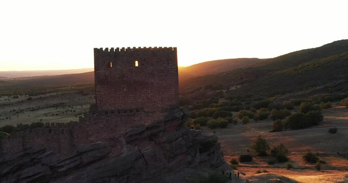 Zafra Castle - Bright Orange Sun At Sunset Over The Mountain Shining Behind The Castillo de Zafra In Guadalajara, Spain. - aerial reveal