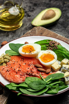 Ketogenic diet breakfast. salmon, avocado, cheese, egg, spinach and nuts. Healthy fats, clean eating for weight loss. vertical image. top view. place for text