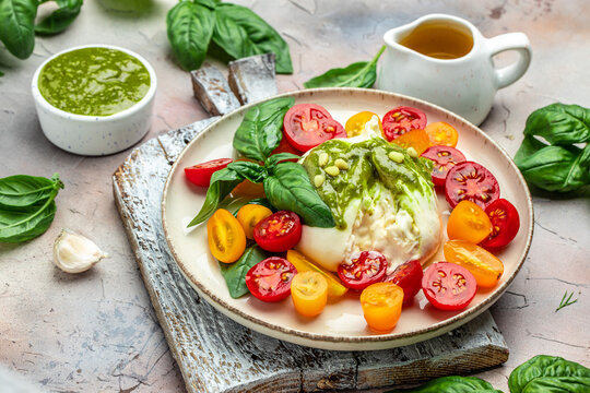 Salad burrata cheese tomatoes and green pesto. Delicious balanced food concept. superfood concept. Healthy, clean eating. Vegan or gluten free diet. top view