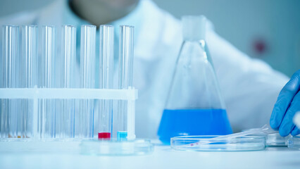 partial view of blurred scientist in latex glove taking pipette on petri dish in laboratory.