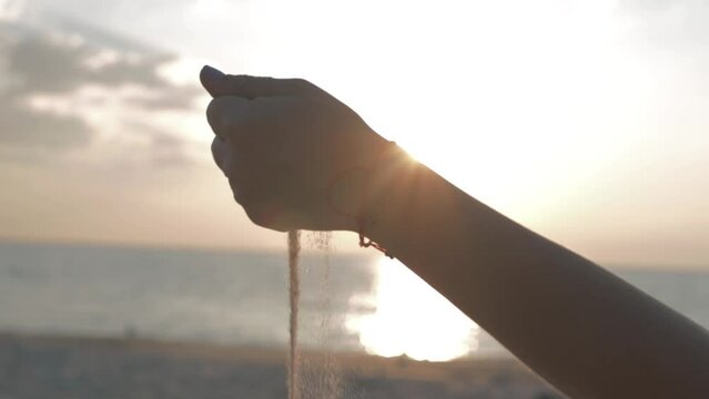girl scatters sand through fingers