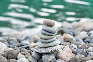 Fototapeta na wymiar Balanced pebble pyramid on the beach with Sea on the background. Life balance, meditation, spa, calmness, harmony concept