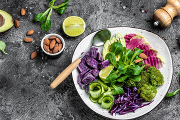 Vegetable vegan salad with sweet potatoes, broccoli, avocado, purple cabbage, cucumber, watermelon radish and almonds. Buddha Bowl. Clean eating, dieting food concept. top view