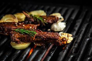 Pork ribs over flaming grill grid, on black background. Barbecue and cooking. baby ribs with barbecue sauce. American cuisine, place for text