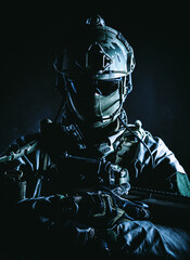 Army soldier in Protective Combat Uniform holding Special Operations Forces Combat Assault Rifle. Studio shot, dark contrast, cropped, black dark background, contour shot