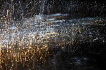 An abstract background with chaotic white and yellow light stripes from a long exposure.