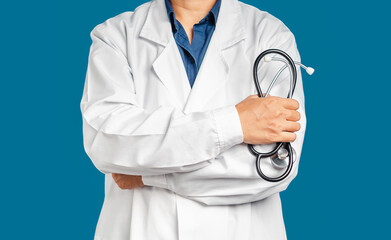 Midsection of a doctor in uniform holding a stethoscope standing with arms crossed on a blue background