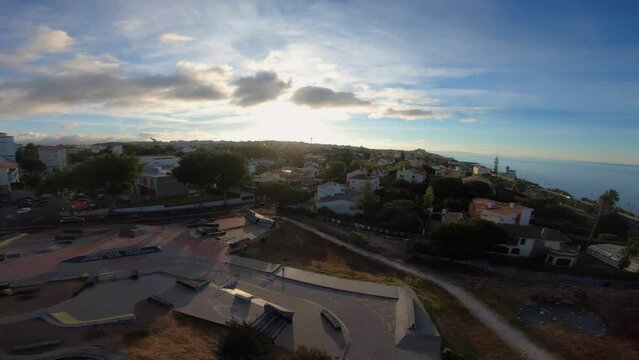 Aerial of large skate park across from downtown Cascais with a huge sunrise. Fish eye view.