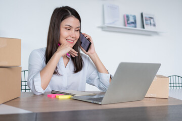 Obraz premium Happy young Asian woman entrepreneur, talk with a supplier and Smile for sale success of online shopping store at home office, Concept of the merchant, small business, online business, and eCommerce.