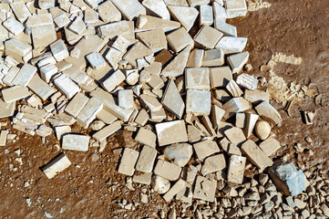 close up of pothole on dirt road covered with fragments of bricks