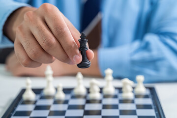 Hand of businessman moving a king chess figure in competition success play. strategy, teamwork,...