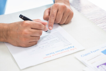 Close up of insurance broker pointing and signing agreement for buying life insurance, hands of sale man represent point document to sign, life insurance protection concept.