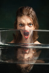 Modern art photography. Funny weird girl's face through glass of water. Object distortion, optical...