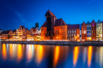 Obraz premium Historic port crane in Gdansk reflected in the Motlawa river at dusk, Poland