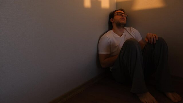 alone depressed man sitting in corner dark room because of problem and sadness in life cheking his phone. Sadnes and spite concept.