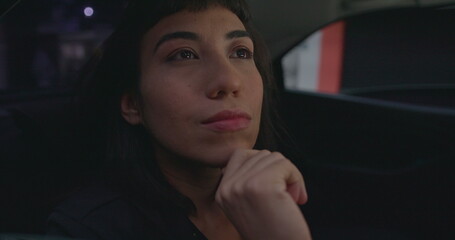 Carefree woman looking at city through car window in car backseat. Happy female passenger closeup face riding taxi cab staring at city buildings.