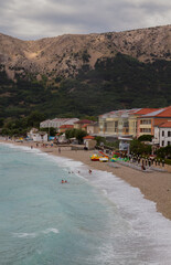 Beach of Baska, Krk, Croatia, on a cloudy day with mountains (vertical)