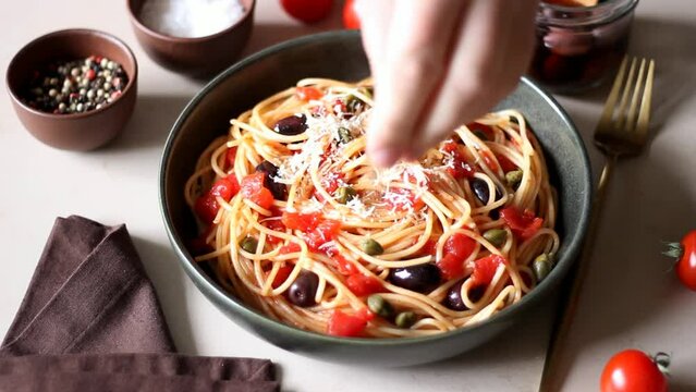 Spaghetti pasta Alla Puttanesca with capers, Kalamata olives, cheese, tomatoes and anchovies. Italian food.