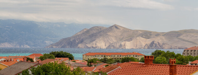 View over the roofs of Baska, island of Krk, Croatia with Mediterranean Sea and mountains (Panorama)