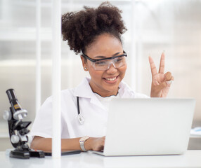 Medical student uses laptop computer and technology for online education training class in medical school. Female multiracial doctor hanging stethoscope offers diagnose and treatment via internet.