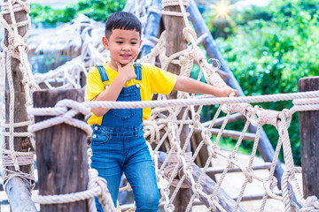 Asian boy put jean enjoy playing rope climbing at the playground. Children's adventure concept