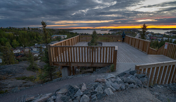 An unrecognizable person stands on a viewpoint watching the Sunrise over Old Town in Yellowknife