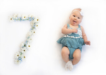 Little caucasian newborn baby girl in a blue dress. 7-month-old baby	