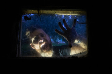scary man behind window with spider nets at night Halloween horror background