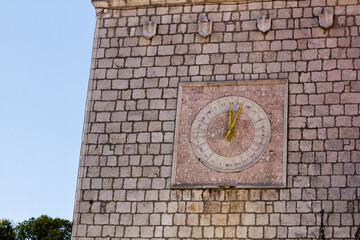 Ancient stone wall of old building with sundial at Krk, Croatia