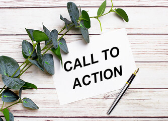 On a light wooden table, there is a eucalyptus branch, a fountain pen and a sheet of paper with the text CALL TO ACTION