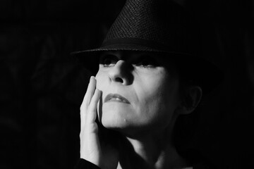 Close-Up schwarzweiß Porträt einer Frau vor schwarzen Hintergrund mit Hut 