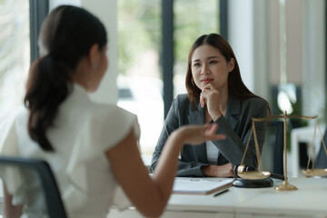 Business woman and lawyers discussing contract papers with brass scale on wooden desk in office....