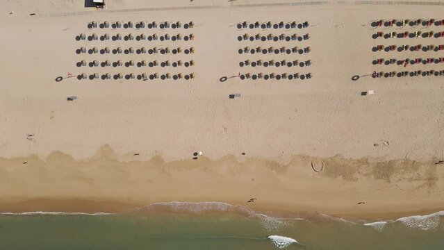 Aerial view of parasols on the beach in early morning facing the ocean in Alvor township, Algarve region, Portugal.