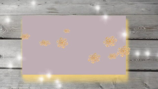 Flying golden snowflakes and blinking lights on wooden grey background . Stop motion animation holidays concept