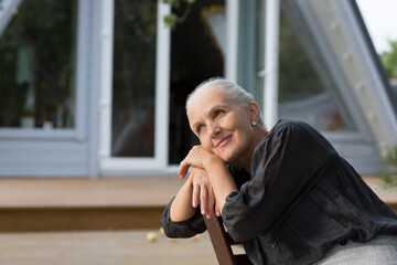 portrait of a cheerful elderly woman in the garden about her home. Enjoying the little things. spends time in nature in summer