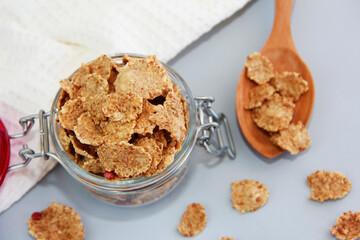 sweet dry dietary wheat muesli in a transparent glass jar and decorative spoon