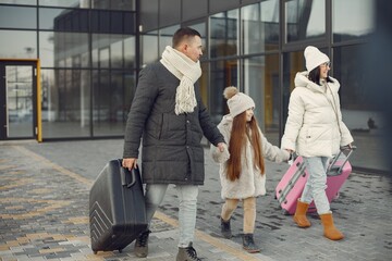Mother, father and daughter with luggage going from airport terminal